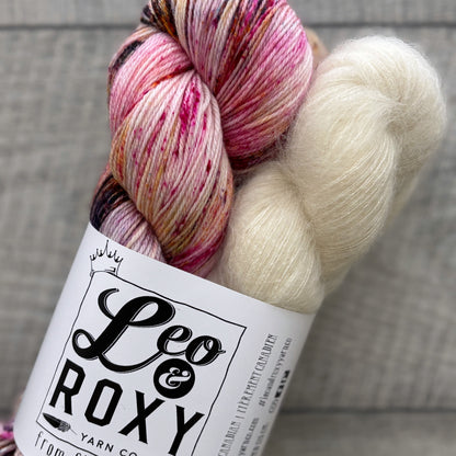 Colorful skein of yarn with a 'Leo & Roxy Yarn Co' label on a wooden surface.
